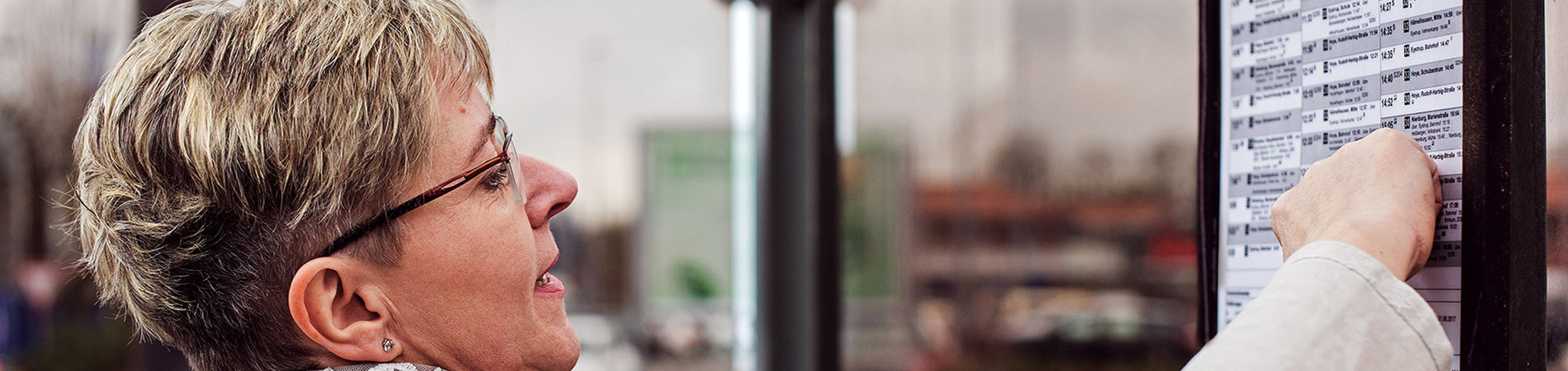 Dieses Bild zeigt eine Frau die an einer Informationstafel nach Informationen sucht