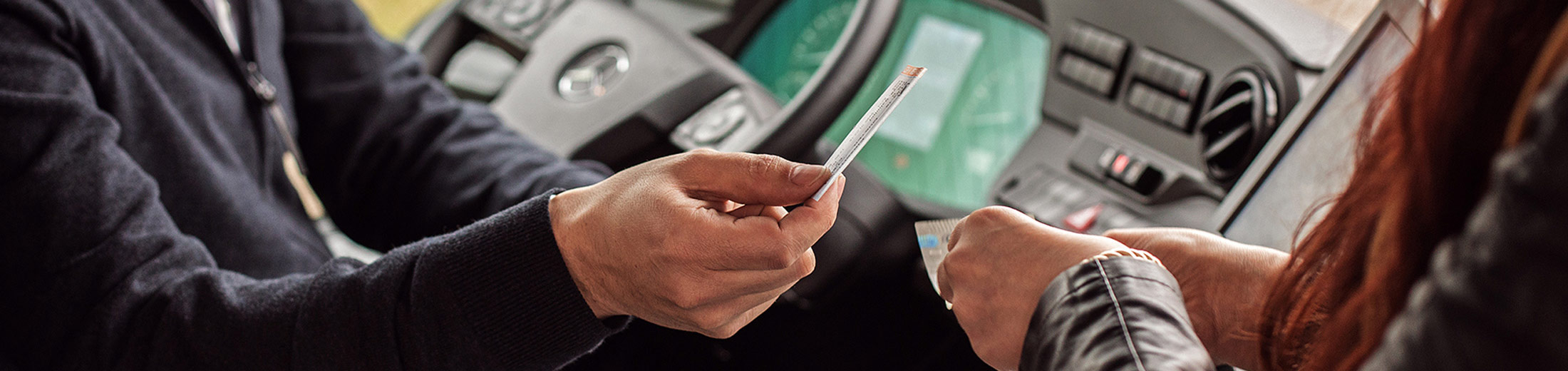 Dieses Bild zeigt die Hand eines Busfahrers, der ein Ticket hält